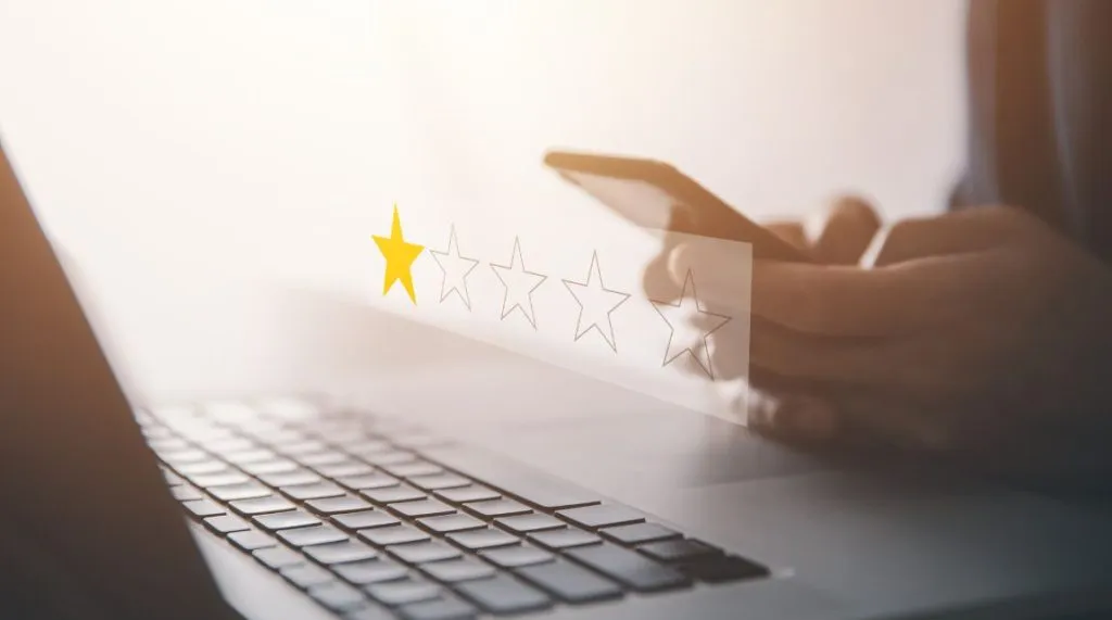 An image of someone sat by their laptop, looking at their phone, with a five star rating system overlaid