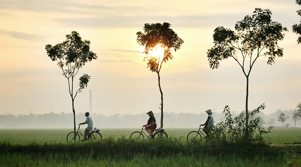 Three people on bikes in rural Indonesia, a country where digital banking is being used to tackle financial inclusion