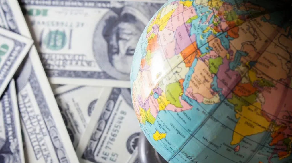 A photo of a globe on a pile of dollars